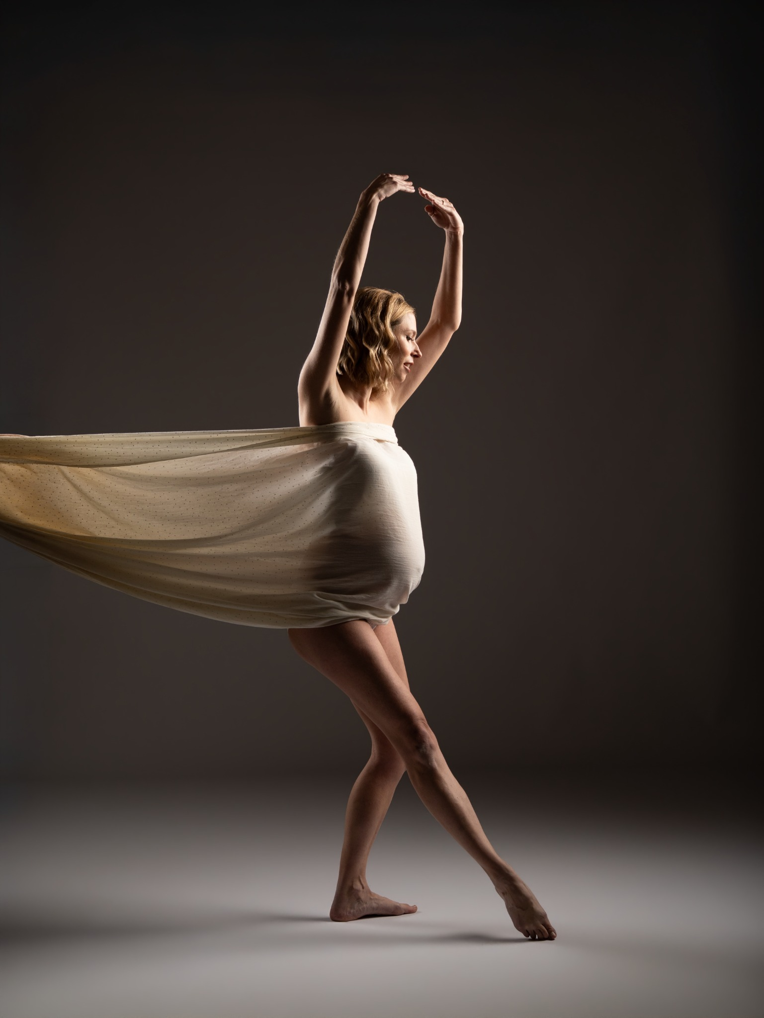 Bailarina con vestido blanco en estudio oscuro