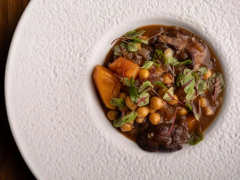 Guiso de carne y verduras servido en plato blanco