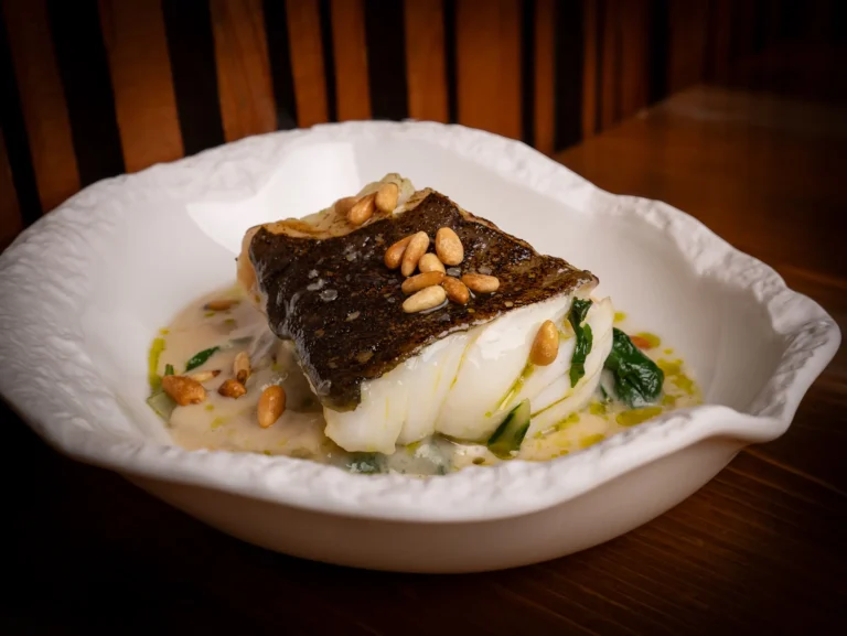 Pescado con crema y piñones en una vajilla artesanal