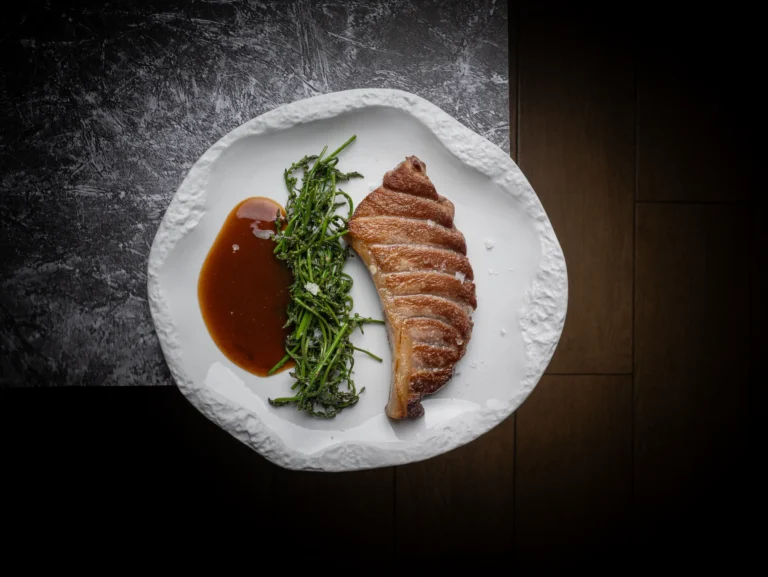 Carne laminada con salsa y hierbas en vajilla blanca