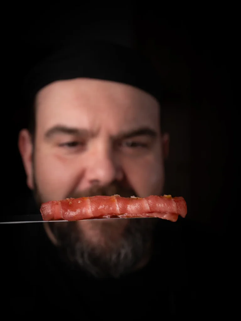 Cocinero sosteniendo una elaboración con gamba roja