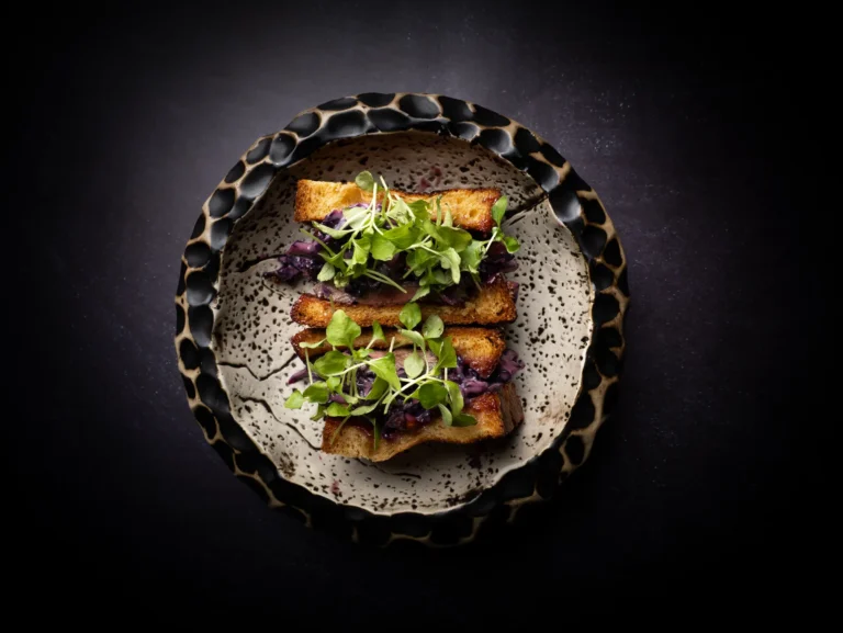 Sándwich gourmet presentado sobre vajilla oscura