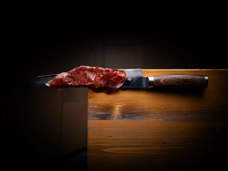 Cuchillo y pieza de carne sobre una superficie de madera