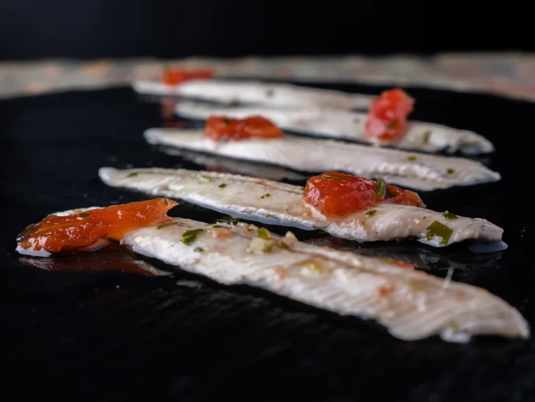 Filetes de boquerón dispuestos sobre una superficie oscura