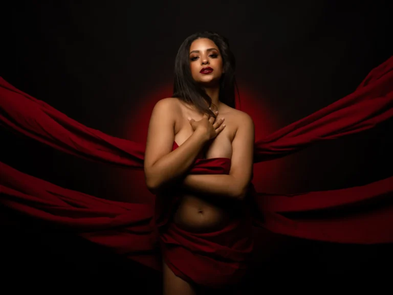 Retrato editorial de mujer envuelta en tela roja sobre fondo oscuro