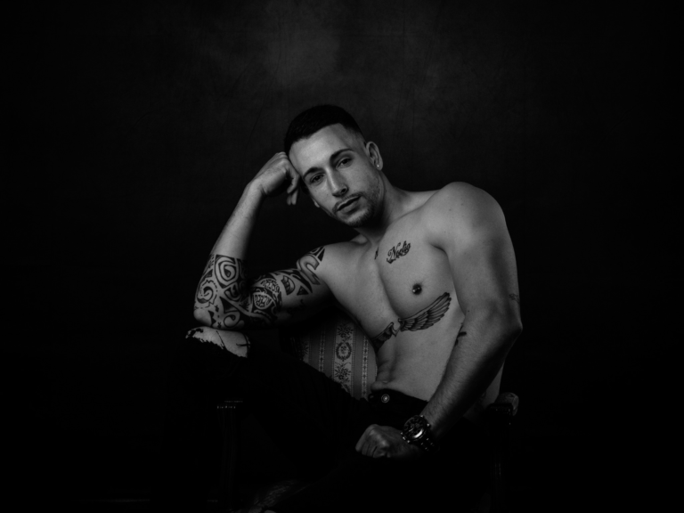 Retrato en blanco y negro de un hombre tatuado sobre fondo oscuro