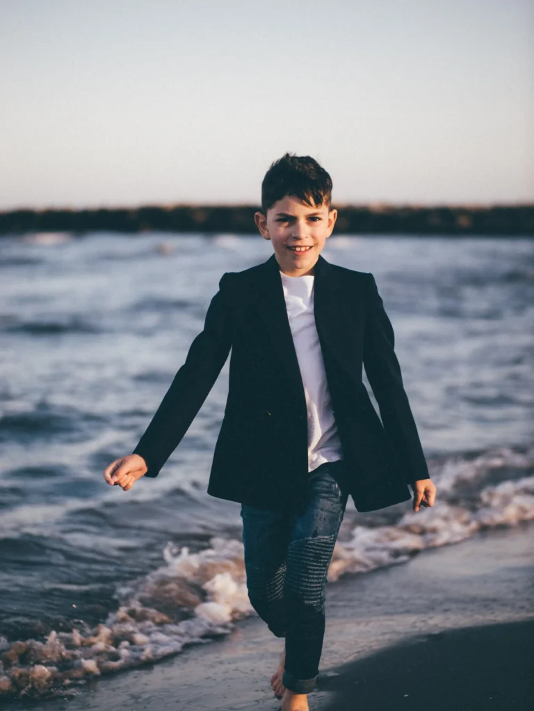 Niño vestido de comunión caminando junto al mar