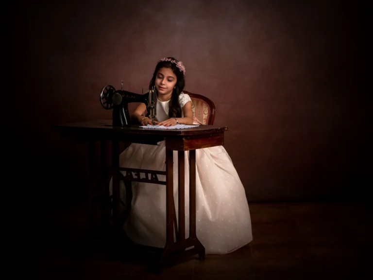 Niña junto a una máquina de coser en una escena de estudio