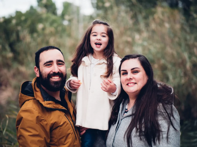 Familia riendo con su hija durante una sesión exterior