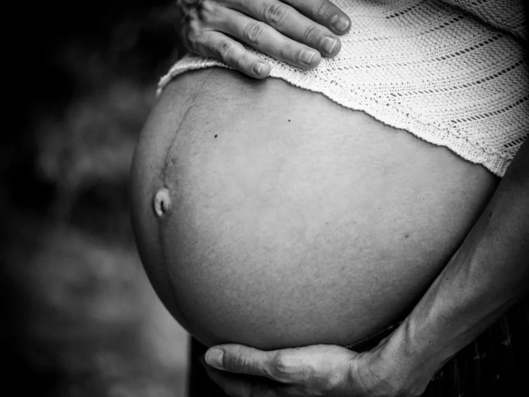 Detalle en blanco y negro de un vientre de embarazo entre unas manos