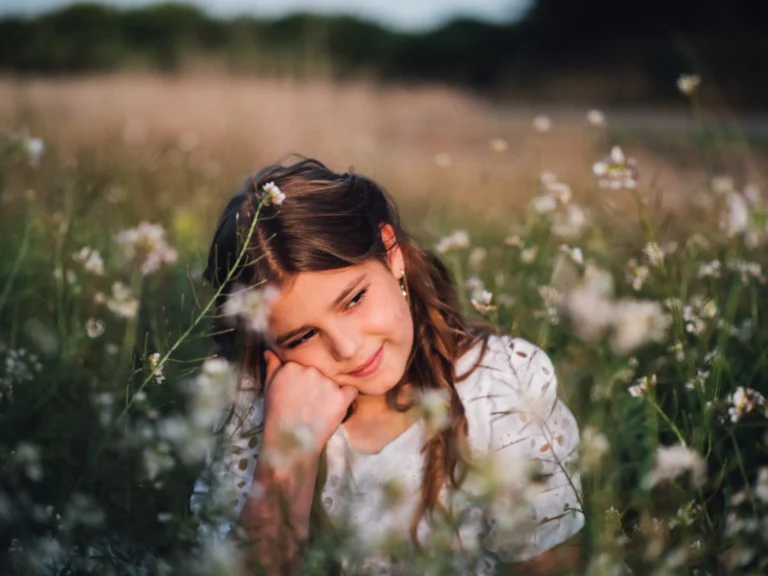 Niña agachada entre flores en el campo