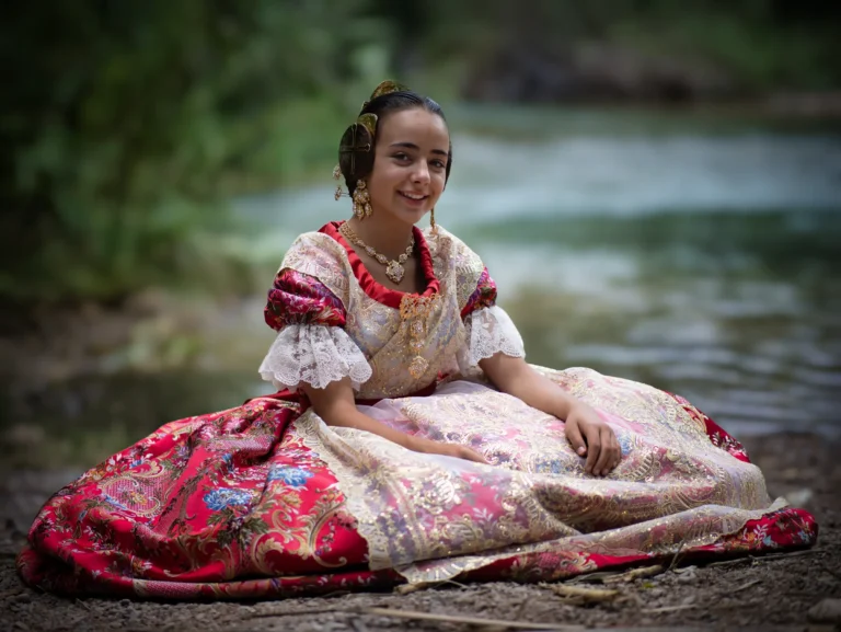 Mujer con indumentaria tradicional valenciana sentada junto al agua