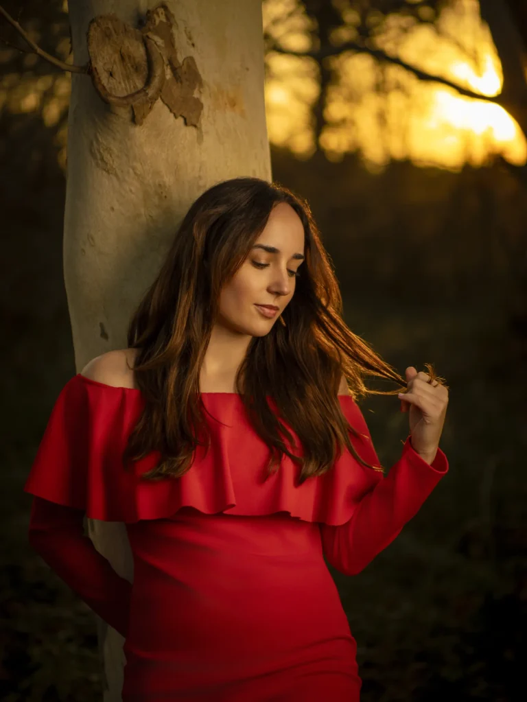 Mujer con vestido rojo junto a una columna de piedra