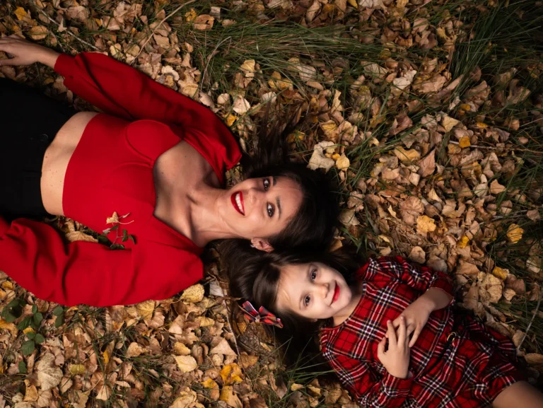 Mujer y niña con vestidos rojos tumbadas sobre hojas