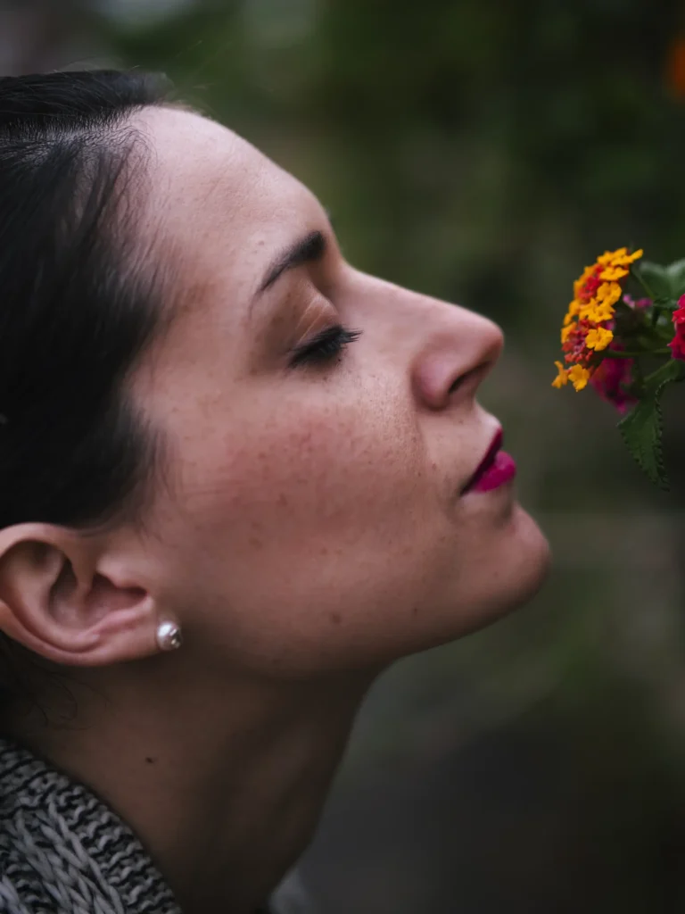 Perfil de mujer observando una flor roja en el bosque