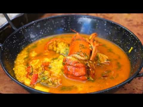 Arroz caldoso con bogavante servido en una paellera negra