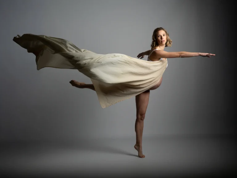 Bailarina en salto con vestido blanco y fondo oscuro