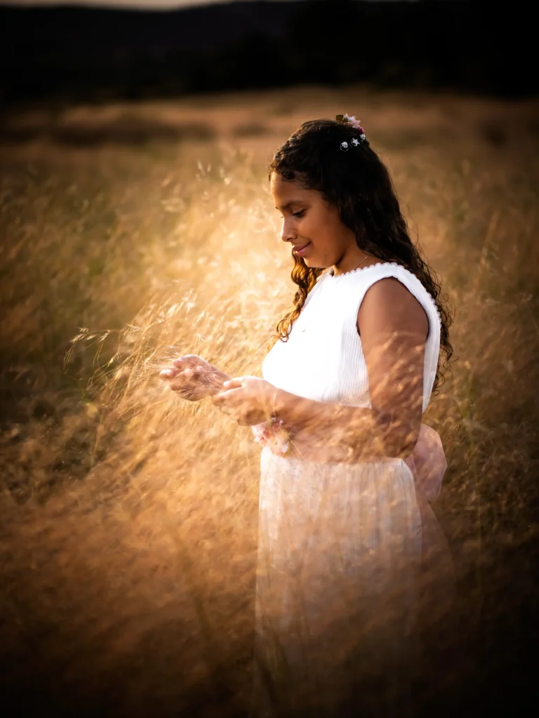 Niña de comunión jugando con pétalos bajo luz dorada